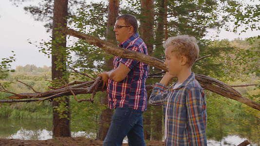 父亲和儿子在夏天的森林里带着干草和火视频的预览图