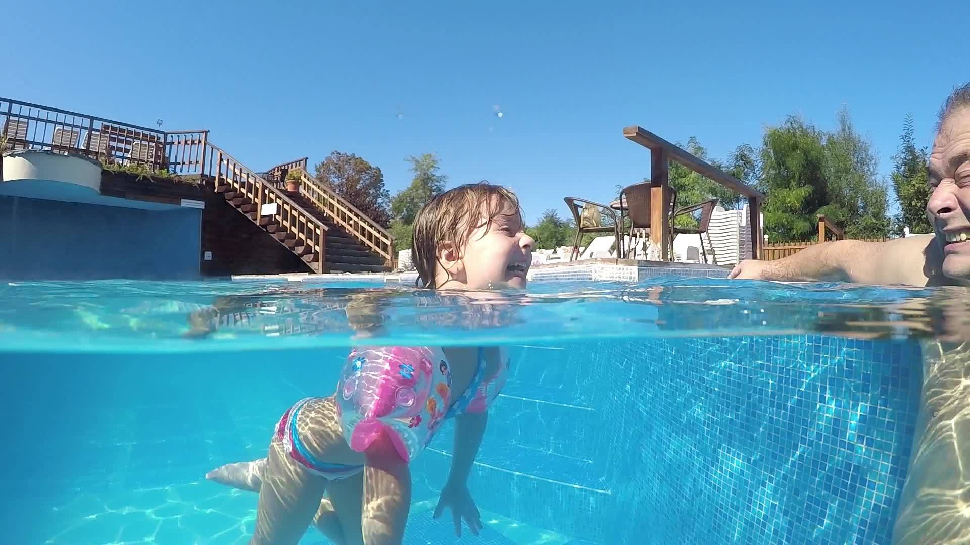 这个有趣的小女孩和她的父亲在热水池里玩得很开心她从嘴里吐出舌头视频的预览图