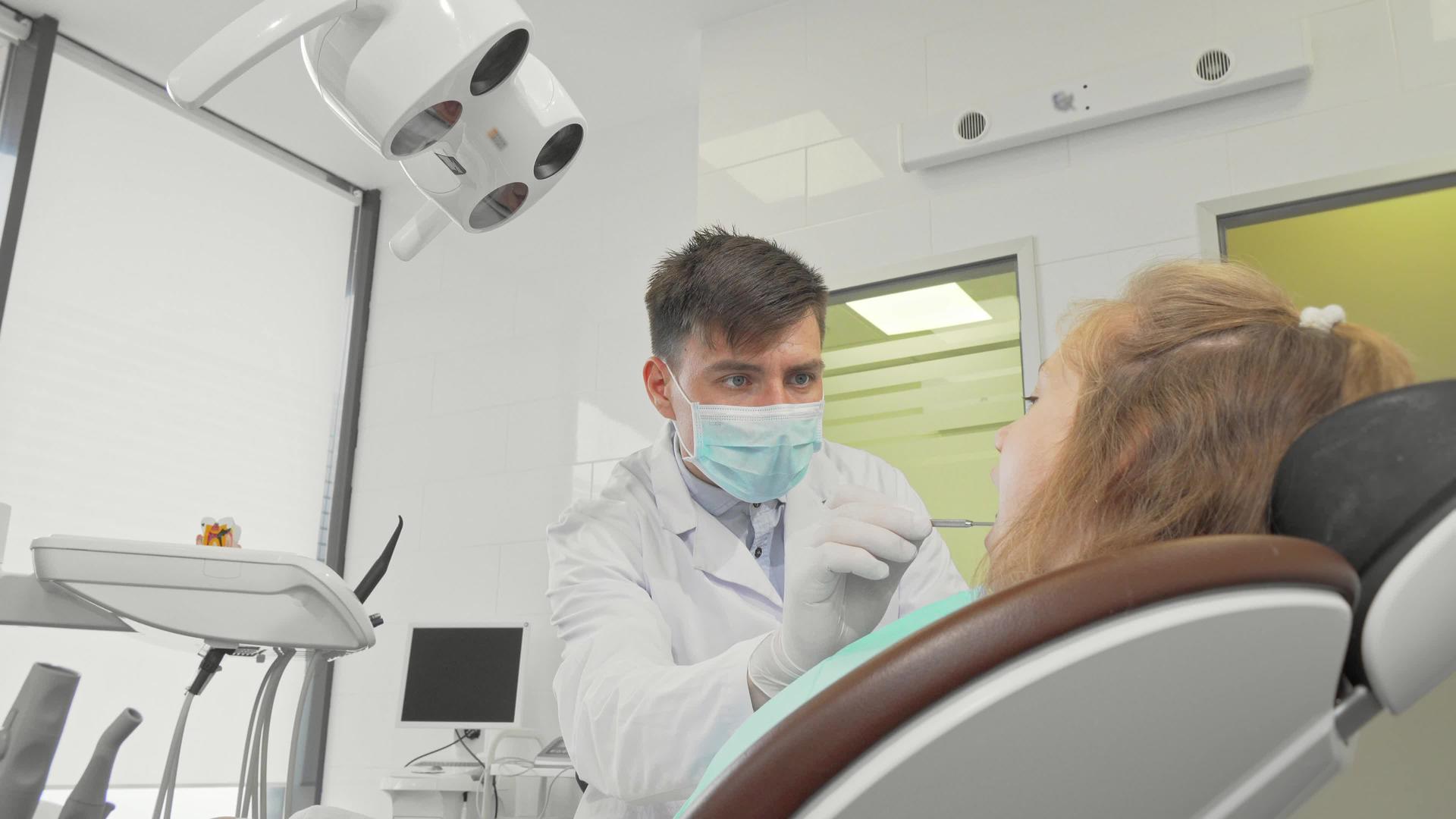在他的诊所工作的男性牙医检查了一个小女孩的牙齿视频的预览图