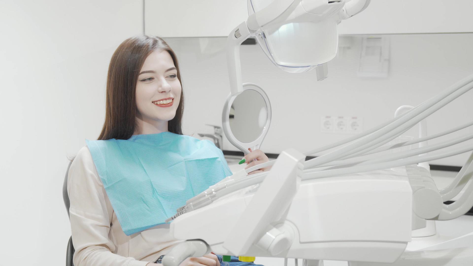 快乐的年轻女性对坐在牙科椅子上的摄像机微笑视频的预览图