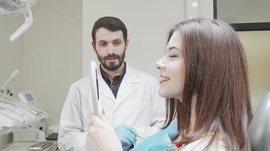 牙医在牙科治疗后照镜子时与患者交谈视频的预览图
