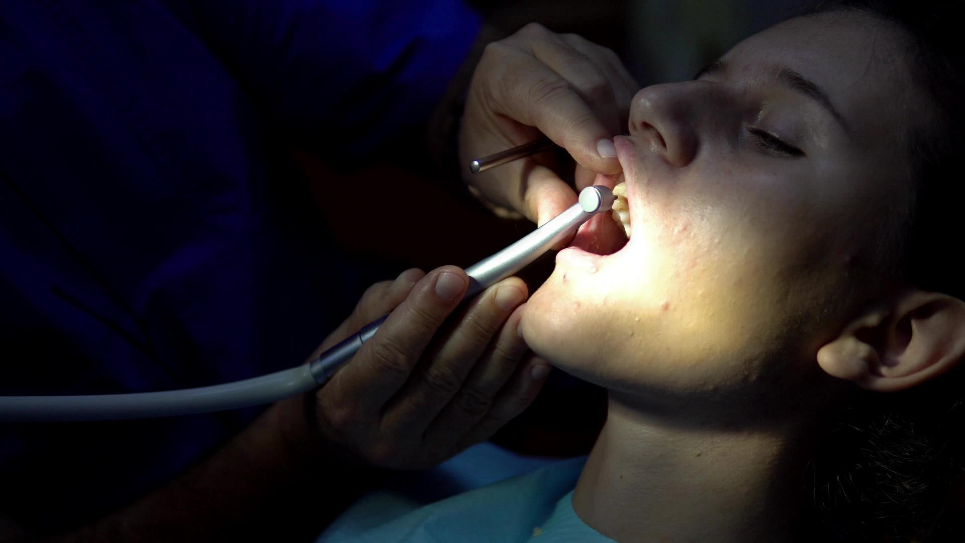 在年轻女性的牙齿上钻涡轮钻孔的牙医视频的预览图