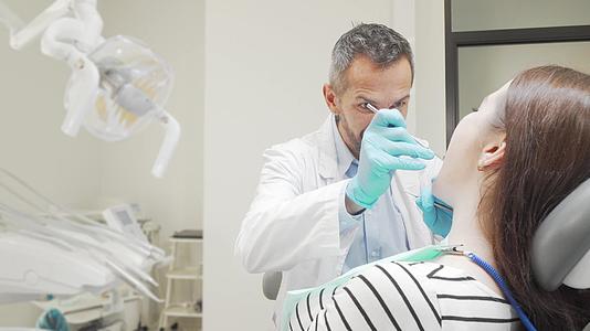 成熟的男性牙医检查女性患者的牙齿视频的预览图