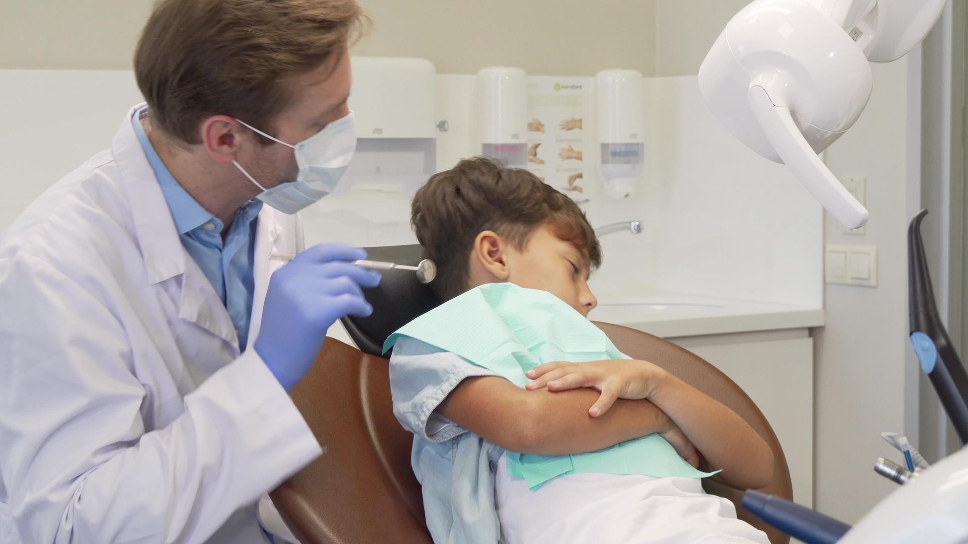 可爱的男孩拒绝向牙医展示他的牙齿看着悲伤和恐惧的眼睛视频的预览图