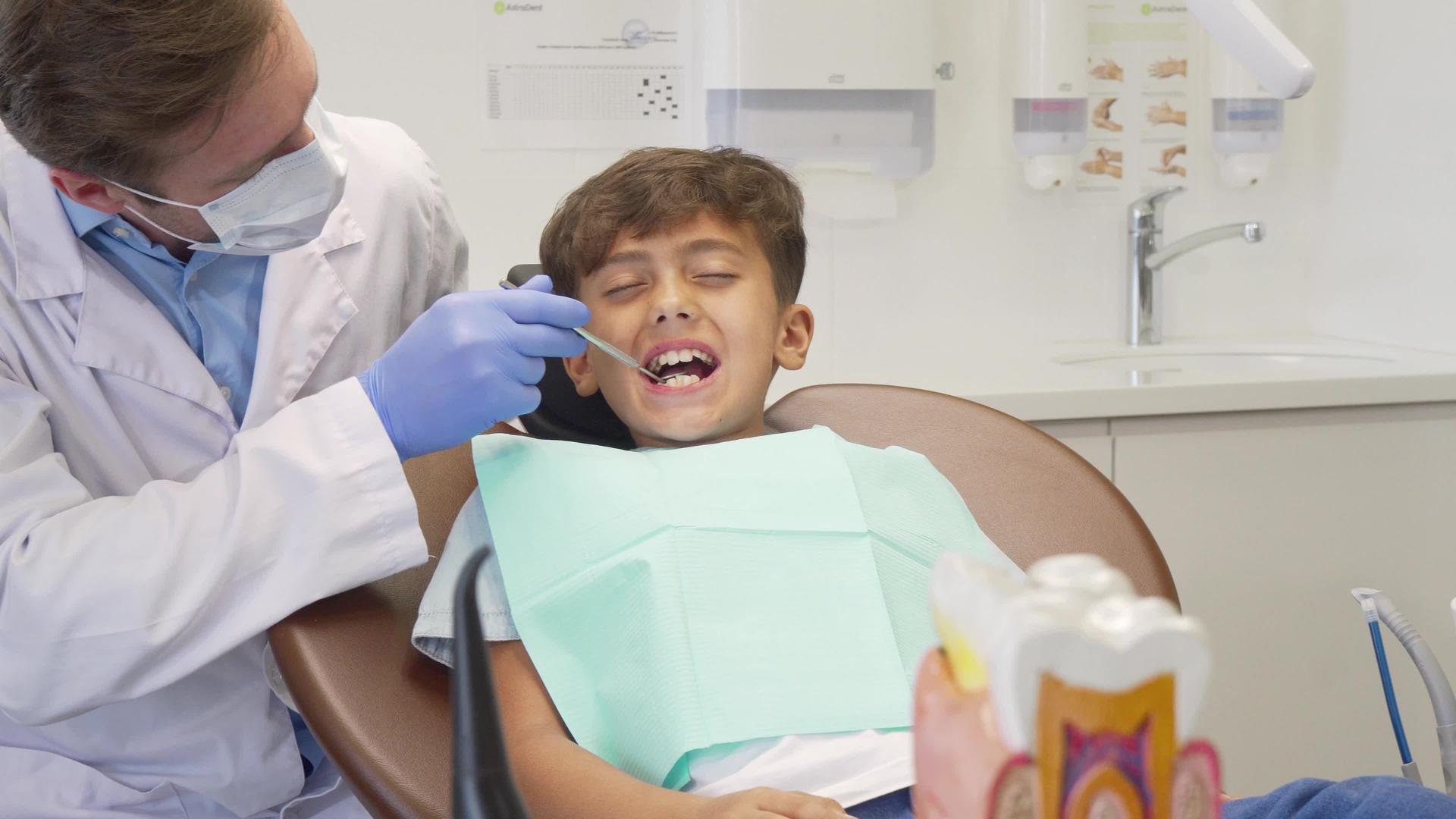 在检查牙齿后成熟的牙医看着那个害怕的小男孩视频的预览图