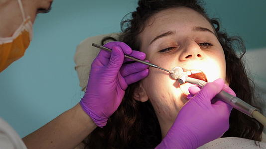 女性牙医使用涡轮机为年轻女性患者工作Dististists视频的预览图