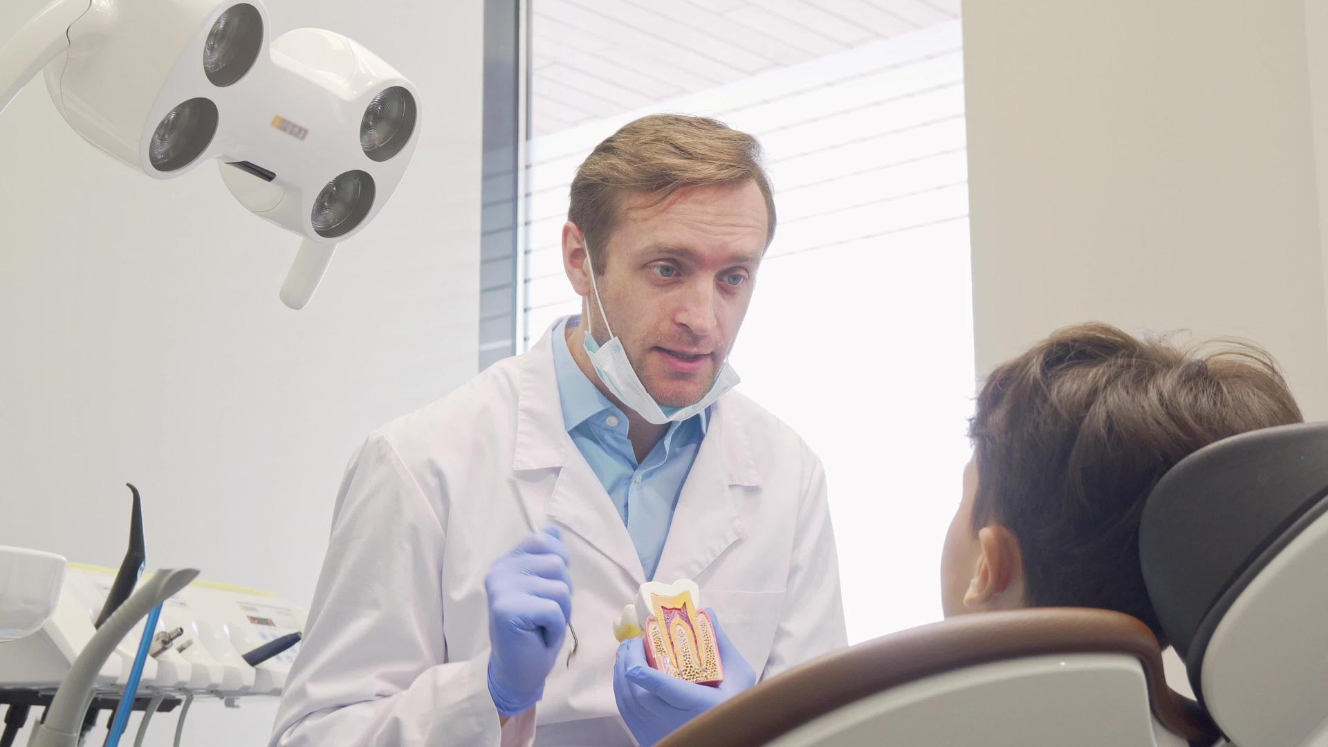 在教育小病人时成熟的男性牙医对着镜头微笑视频的预览图