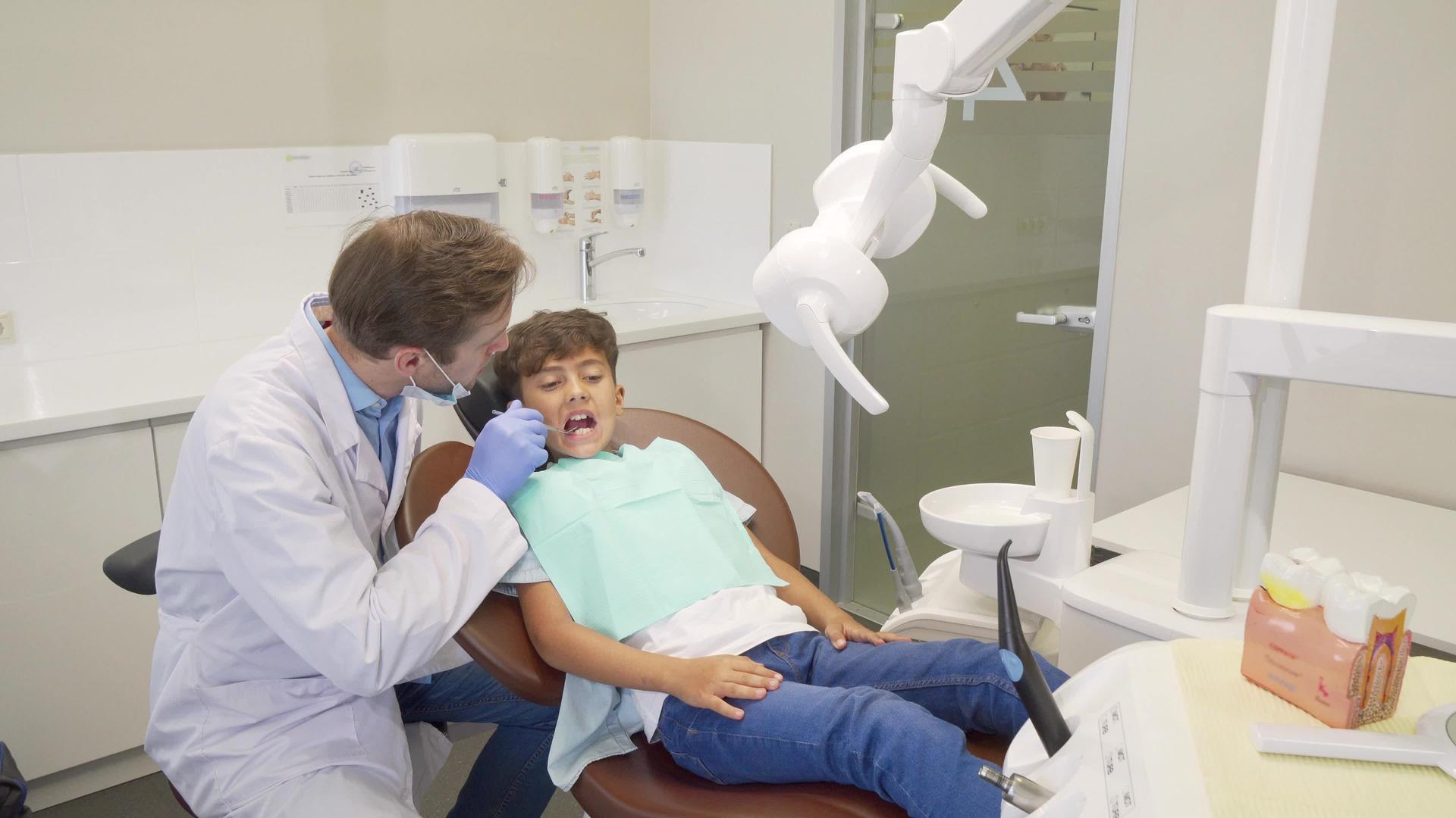 成功的牙科检查后快乐的小男孩在牙医身上长得很高视频的预览图