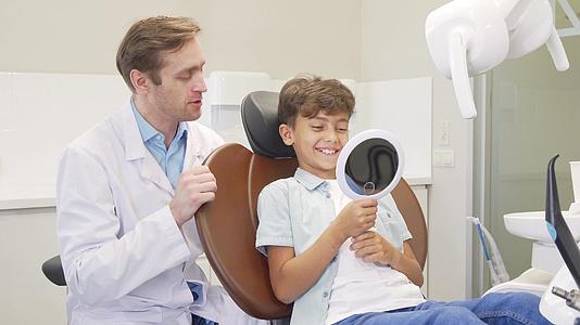 牙科检查后这个可爱的男孩在镜子里检查了他的健康牙齿视频的预览图