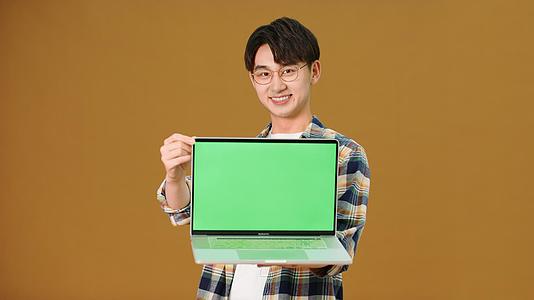 男青年展示笔记本电脑绿幕视频的预览图