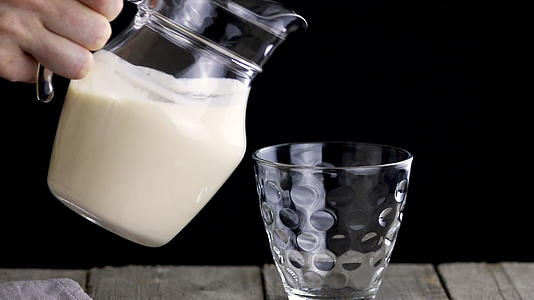 人们把发酵的烤牛奶从一个罐子里倒进玻璃杯里视频的预览图