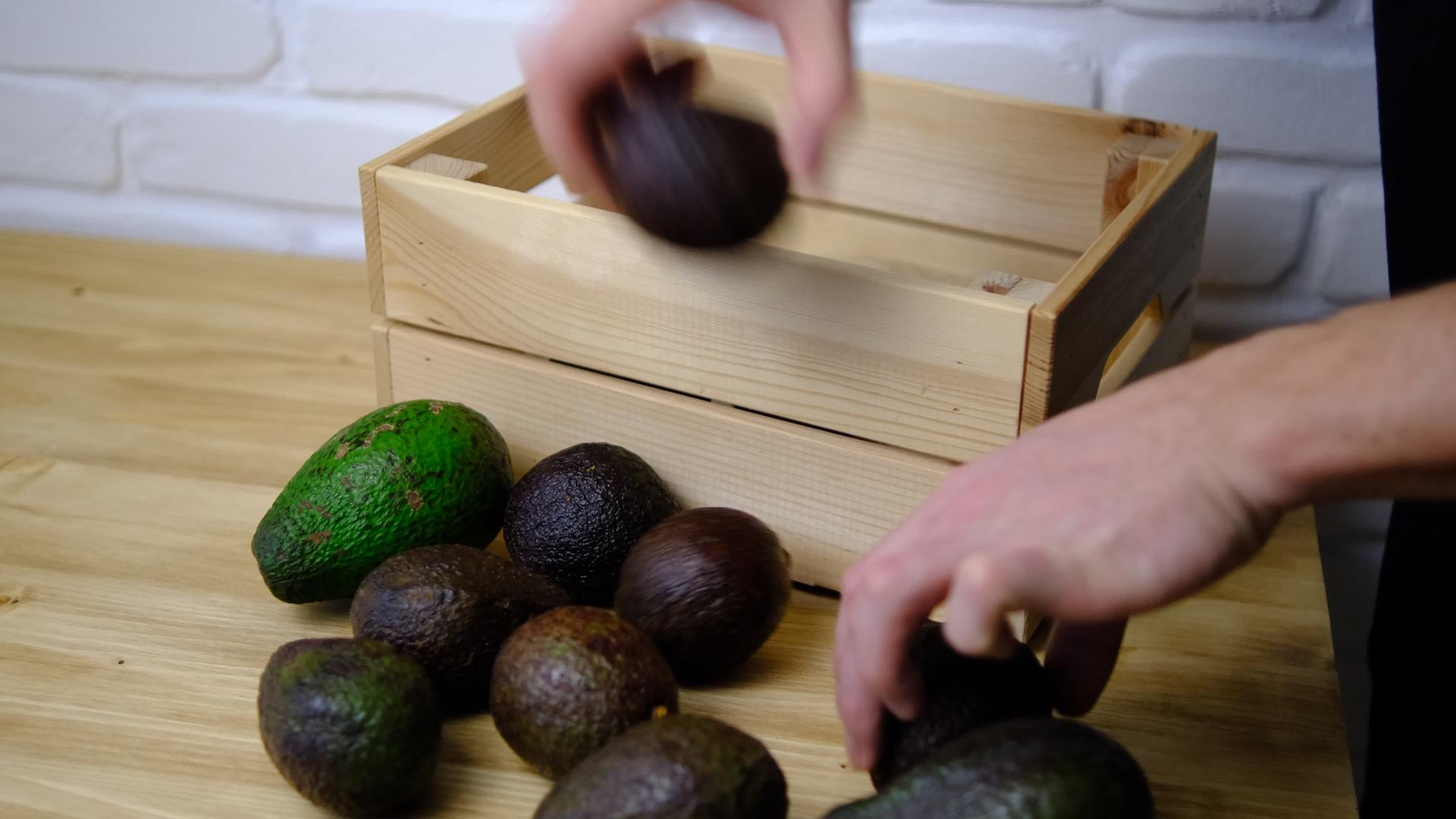 他把鳄梨水果从桌子搬到抽屉里成熟的水果收获桌上的木箱视频的预览图