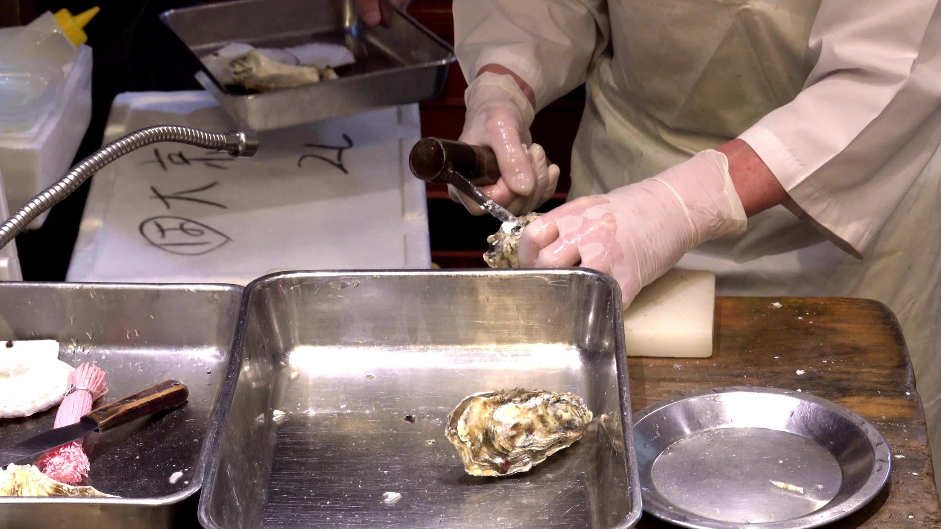 在西尼基市场活手拿着牡蛎和刀子洗发水视频的预览图