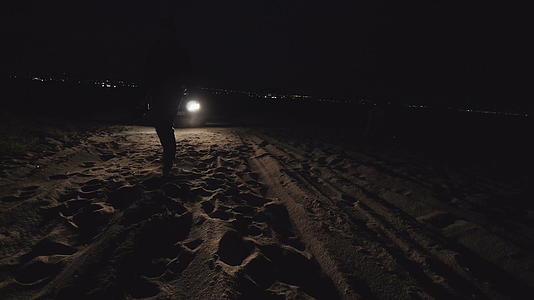 神秘恐怖的人看起来很危险他们在海滩上行走时被前灯照亮视频的预览图