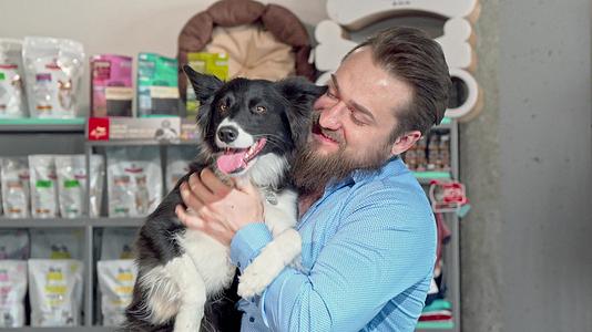 快乐的男人抱着可爱的狗对着镜头微笑视频的预览图