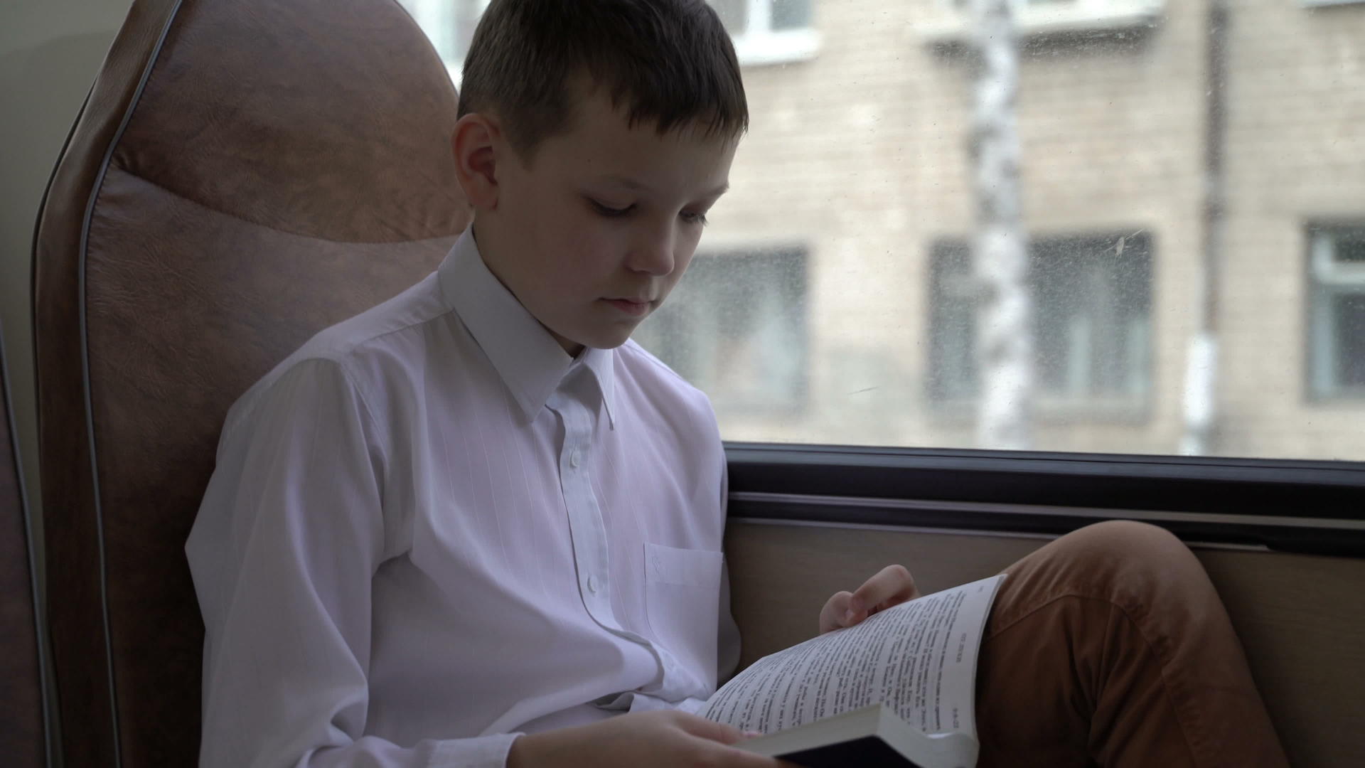 一名年轻的男中学生乘公共汽车穿过城市读了一本书视频的预览图
