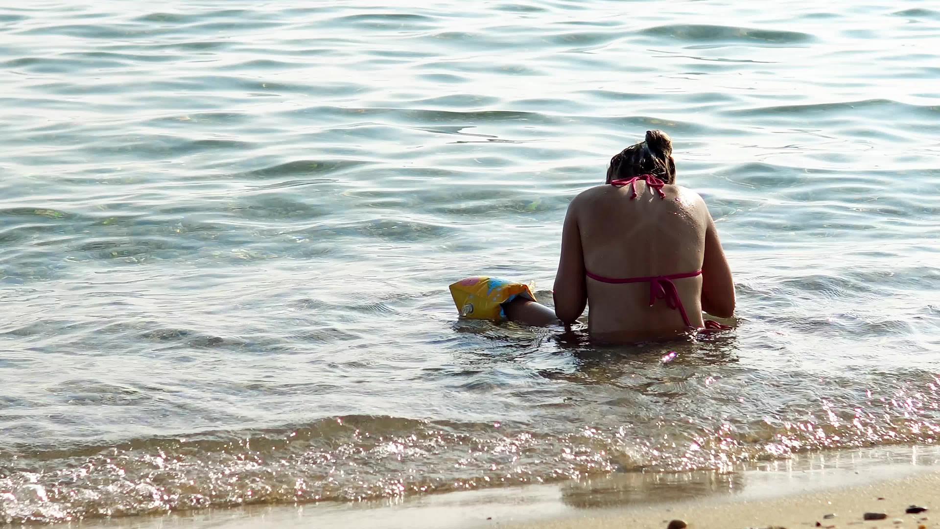 独身女孩坐在浅海的海滩上视频的预览图