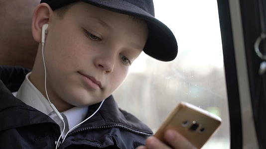 一个男孩在城里乘公共汽车旅行时拍了一张近距离照片他使用智能手机视频的预览图