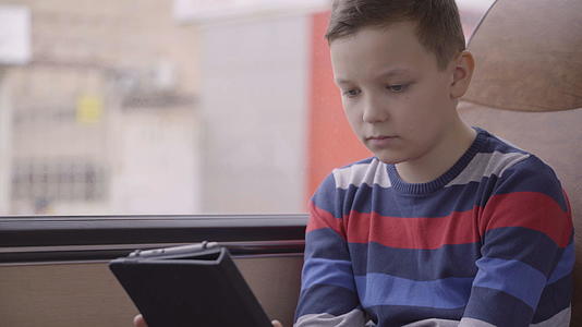 一个年轻男孩使用计算机平板电脑上的社交网络使用公共汽车视频的预览图