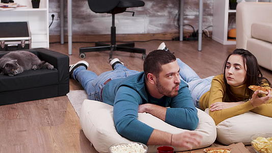 男人和女人躺在地板上看电视视频的预览图