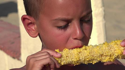 男孩吃新鲜煮熟的玉米视频的预览图