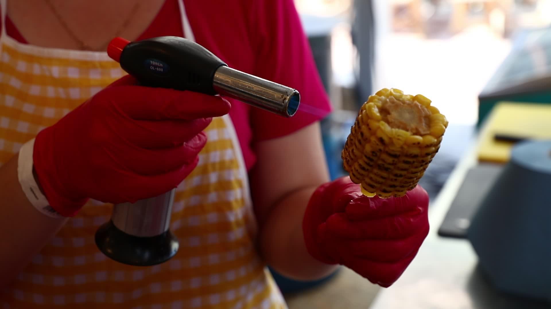 女人用煤气火炬在棍子上煮玉米鳕鱼视频的预览图
