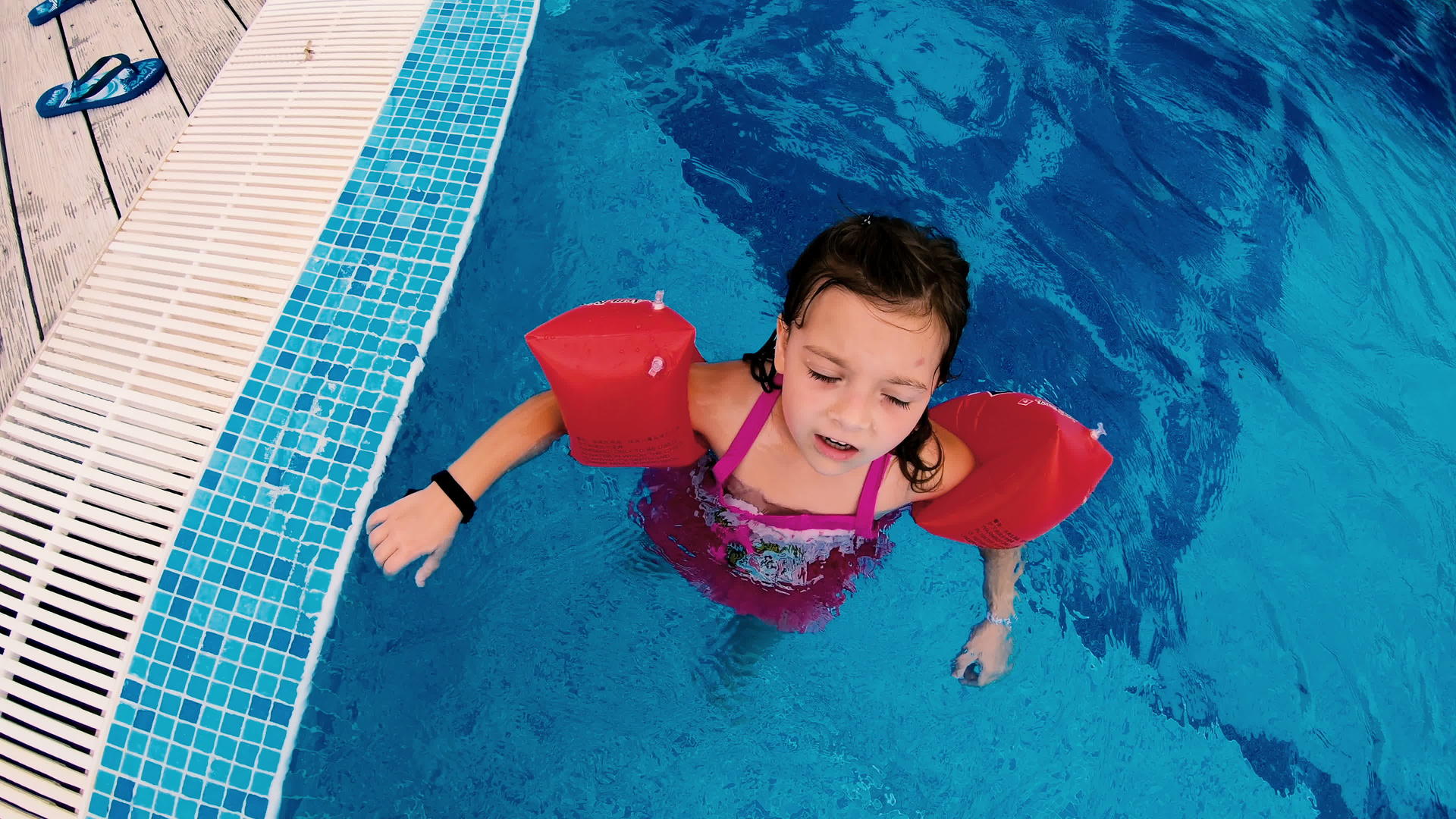 在室外游泳池玩的女孩有充气臂带视频的预览图
