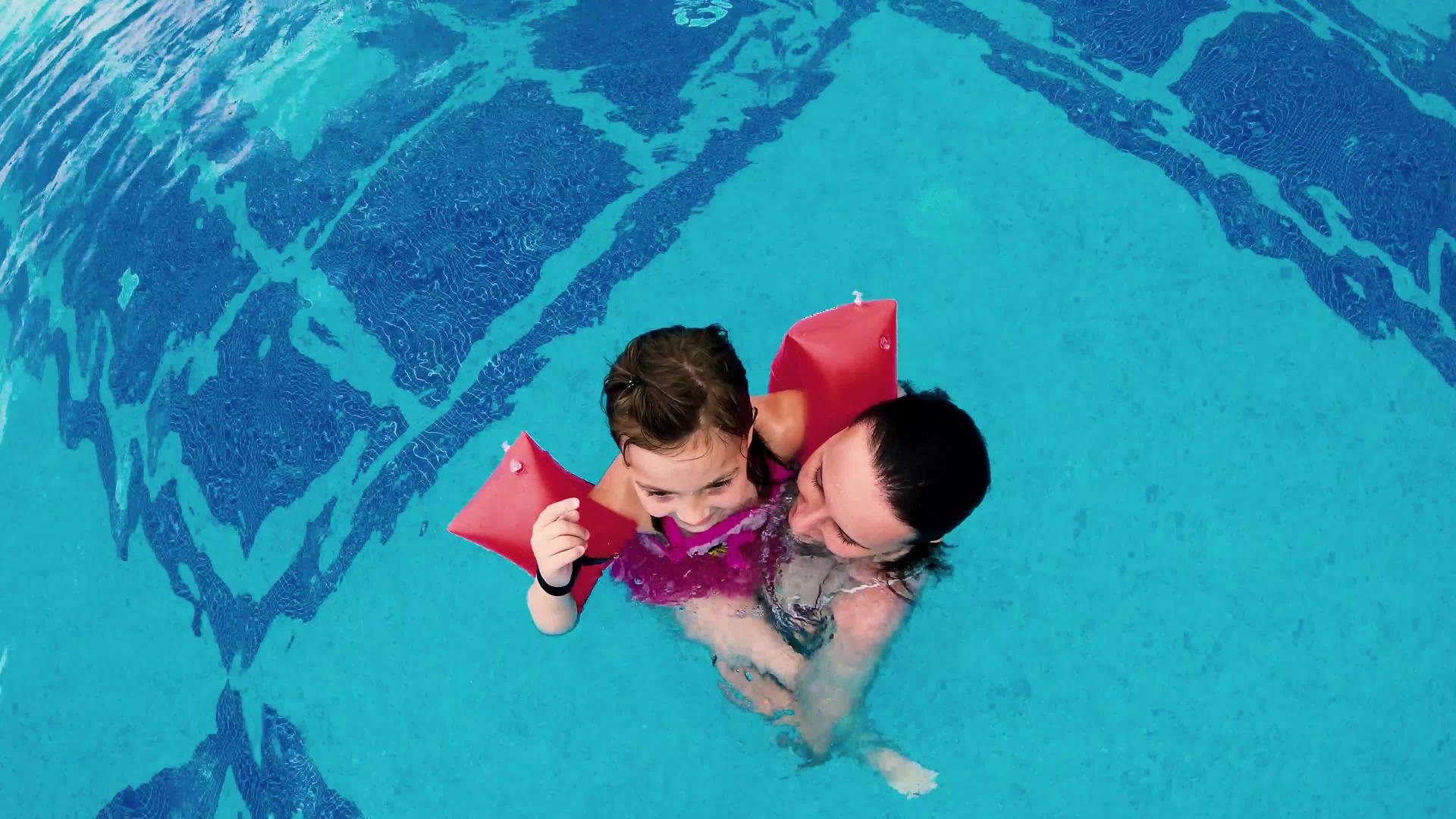 和小妹妹一起玩游泳池跳起来抓相机的充气臂在游泳池里弹奏视频的预览图