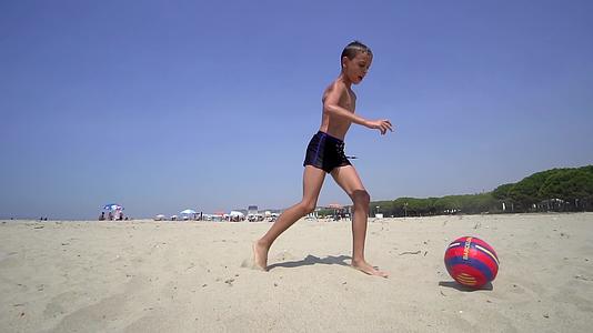 男孩享受在海滩上踢足球的乐趣Standicam视频的预览图