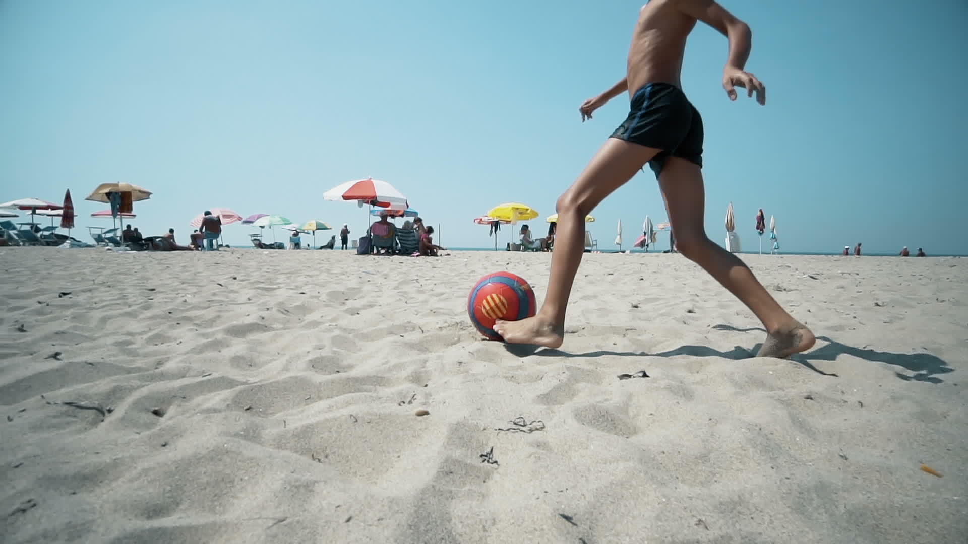 快乐的儿子暑假在海滩上踢足球或踢足球视频的预览图