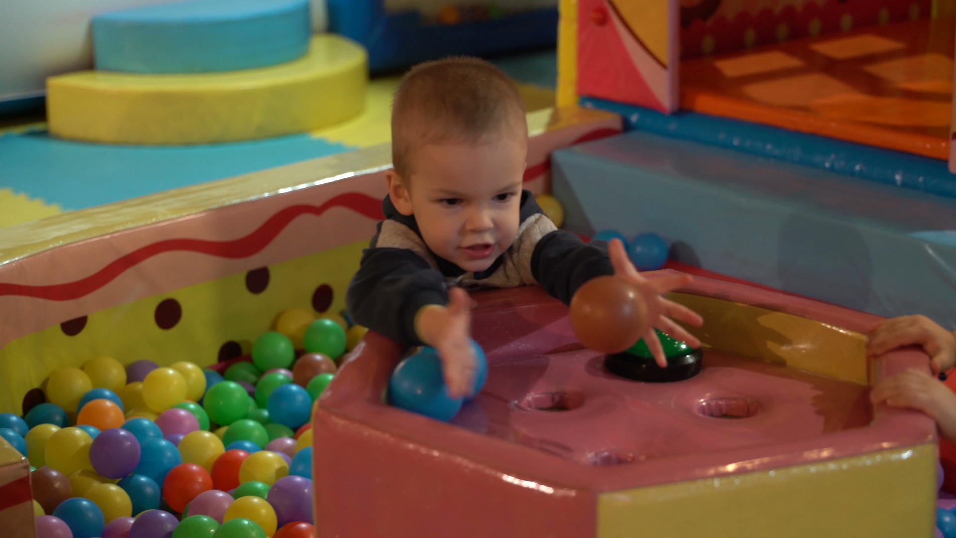 一个两岁的男孩带着五颜六色的塑料球在游泳池的操场上玩耍视频的预览图