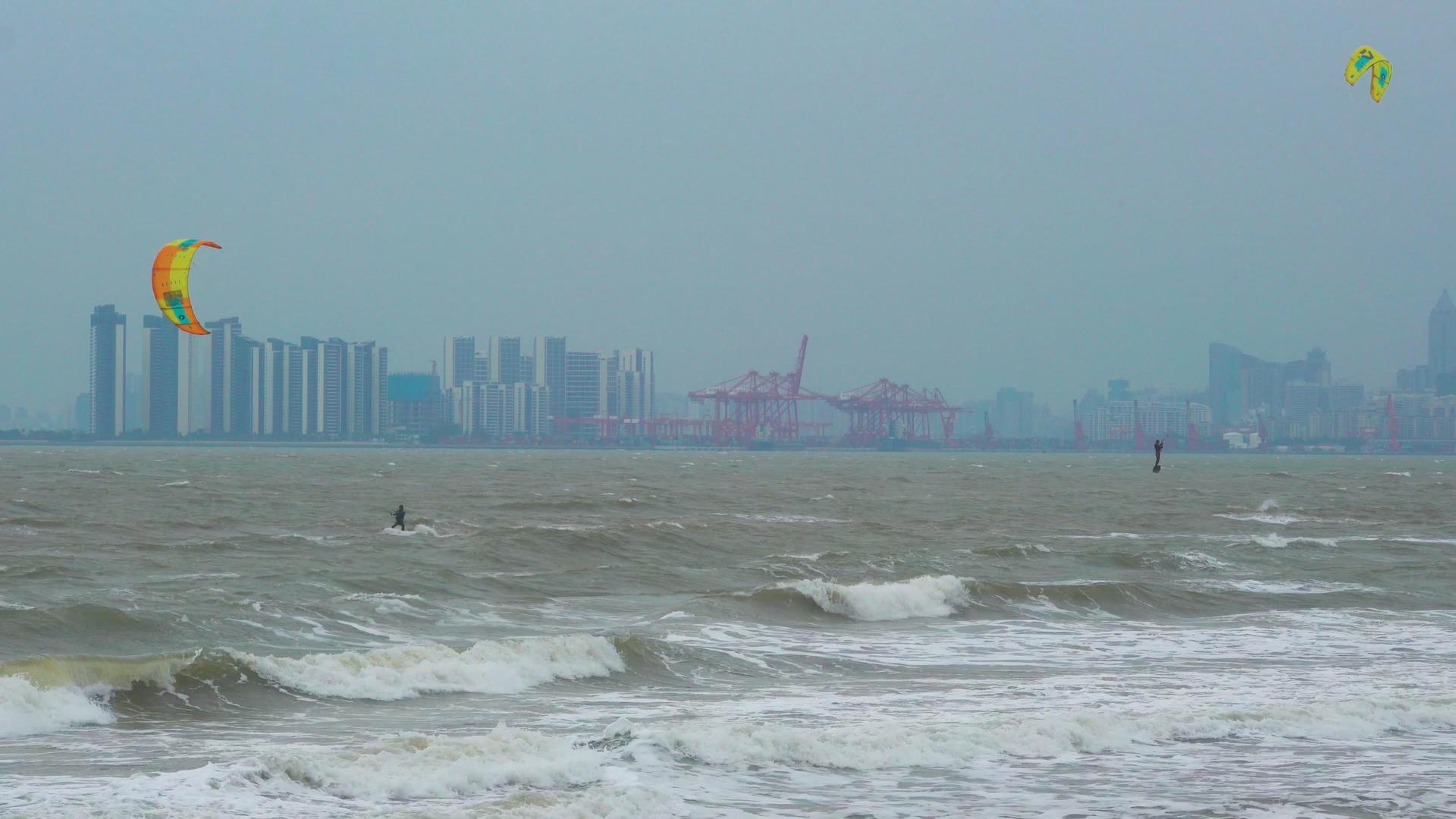4K大风浪天气下海口海边玩冲浪滑翔伞的极限运动者视频素材视频的预览图