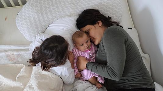 母亲和两个年轻的女儿快乐地躺在床上视频的预览图