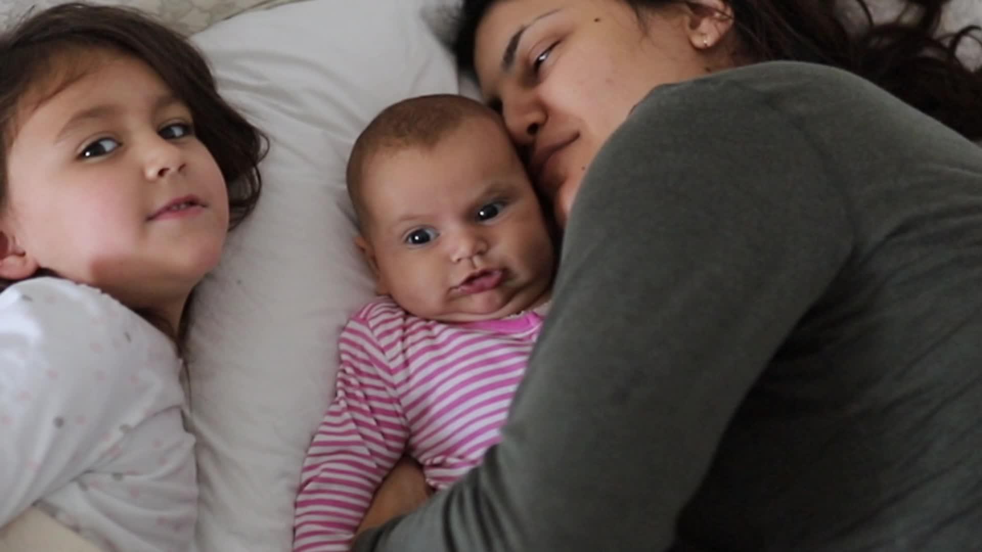 母亲和两个快乐的年轻女儿躺在床上视频的预览图