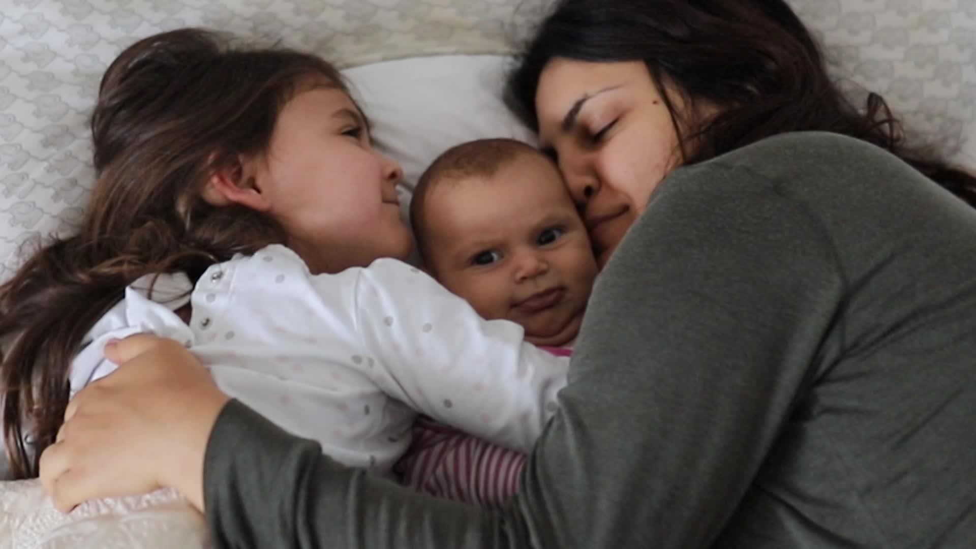 母亲和女儿把最小的妹妹抱在床上视频的预览图