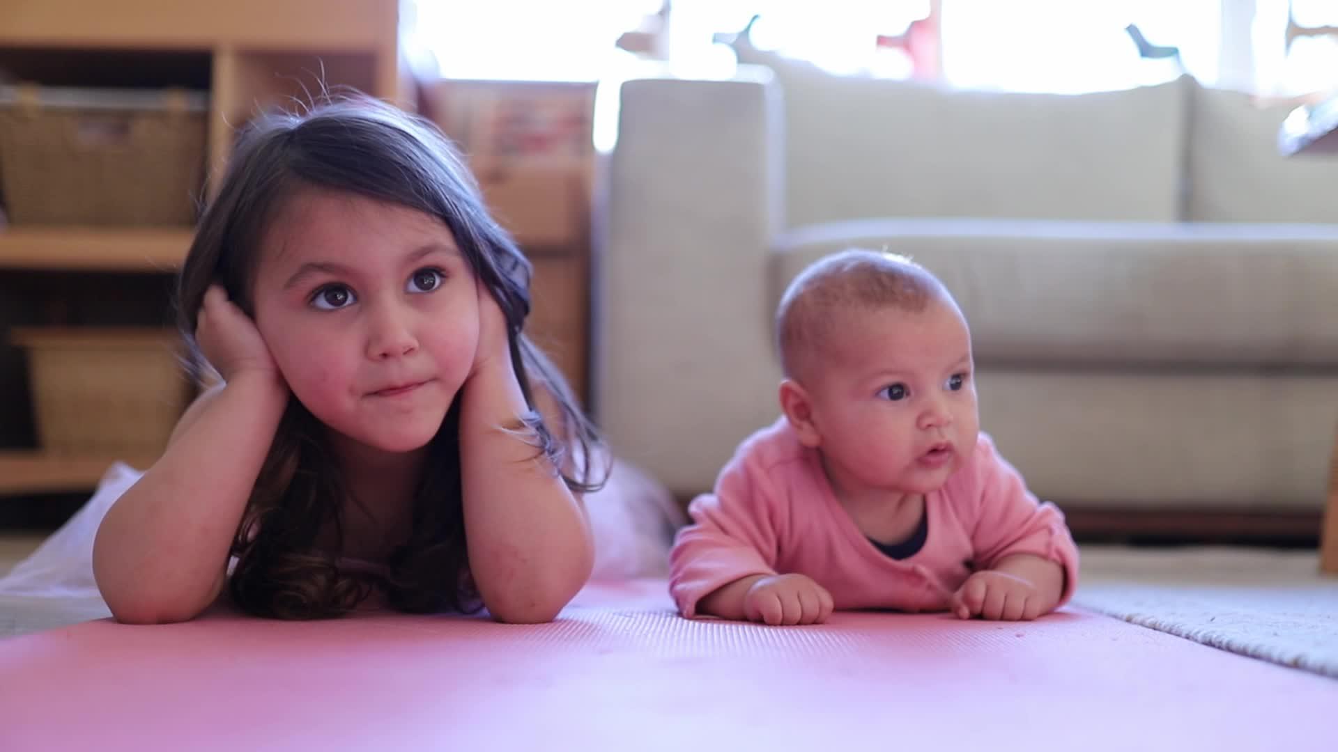小女孩躺在她的小妹妹旁边视频的预览图