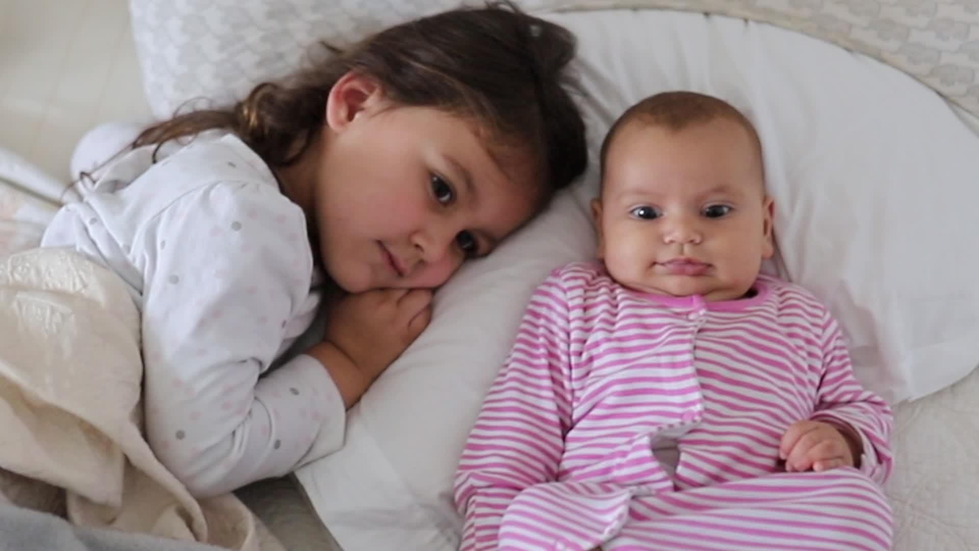 小女孩和她快乐的妹妹睡在床上视频的预览图