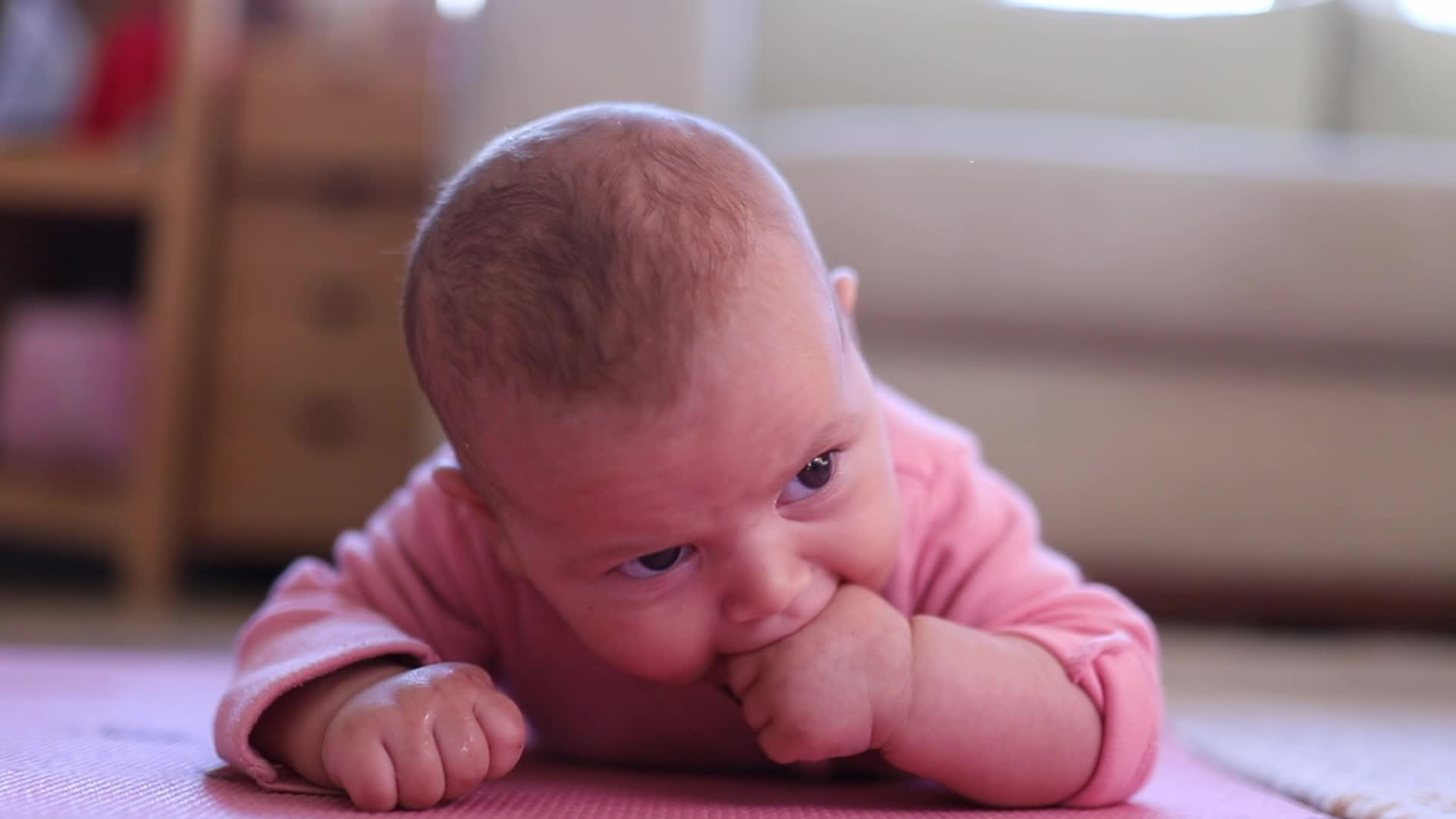 婴儿微笑着躺在粉红色的地毯上视频的预览图