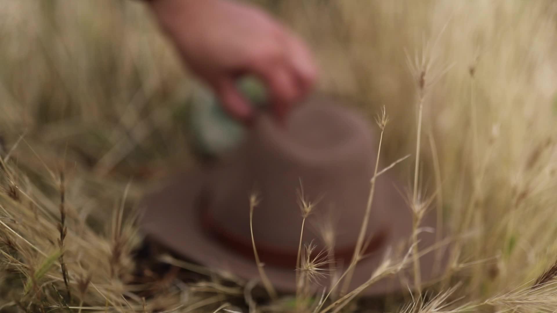 从干草地上捡起一顶模糊的帽子视频的预览图