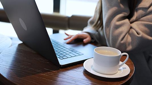 使用笔记本电脑喝咖啡的女青年视频的预览图