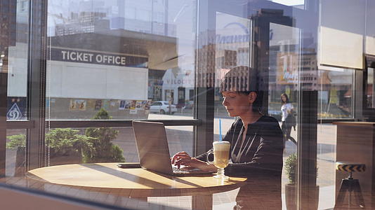 黑发青年在咖啡馆用笔记本电脑享受早晨咖啡视频的预览图