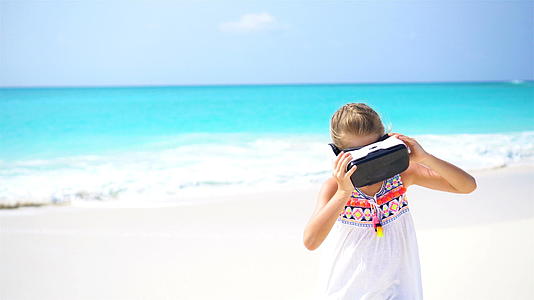 可爱的小女孩在白色的海滩上使用Vr虚拟现实护目镜视频的预览图