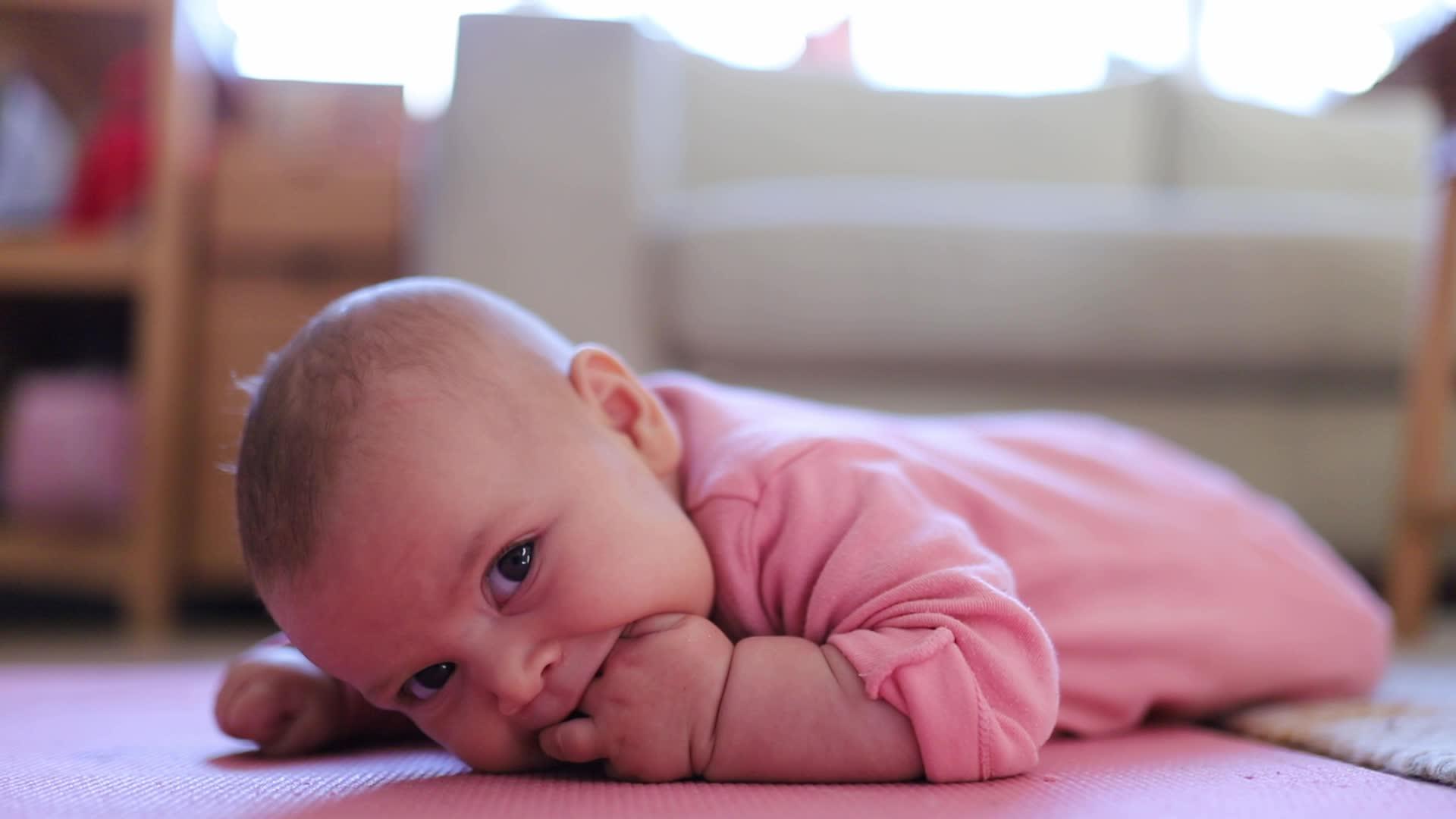 女婴躺在粉红色的地毯上视频的预览图