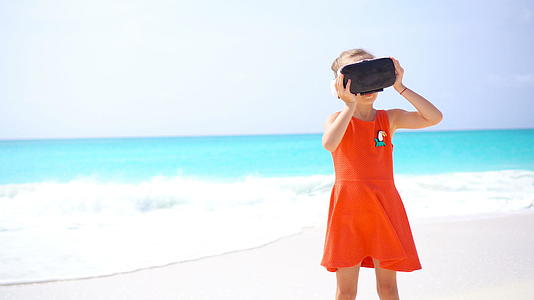 可爱的小女孩在海滩上使用虚拟现实护目镜视频的预览图
