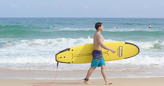 8K男青年抱着冲浪板走在沙滩上视频的预览图