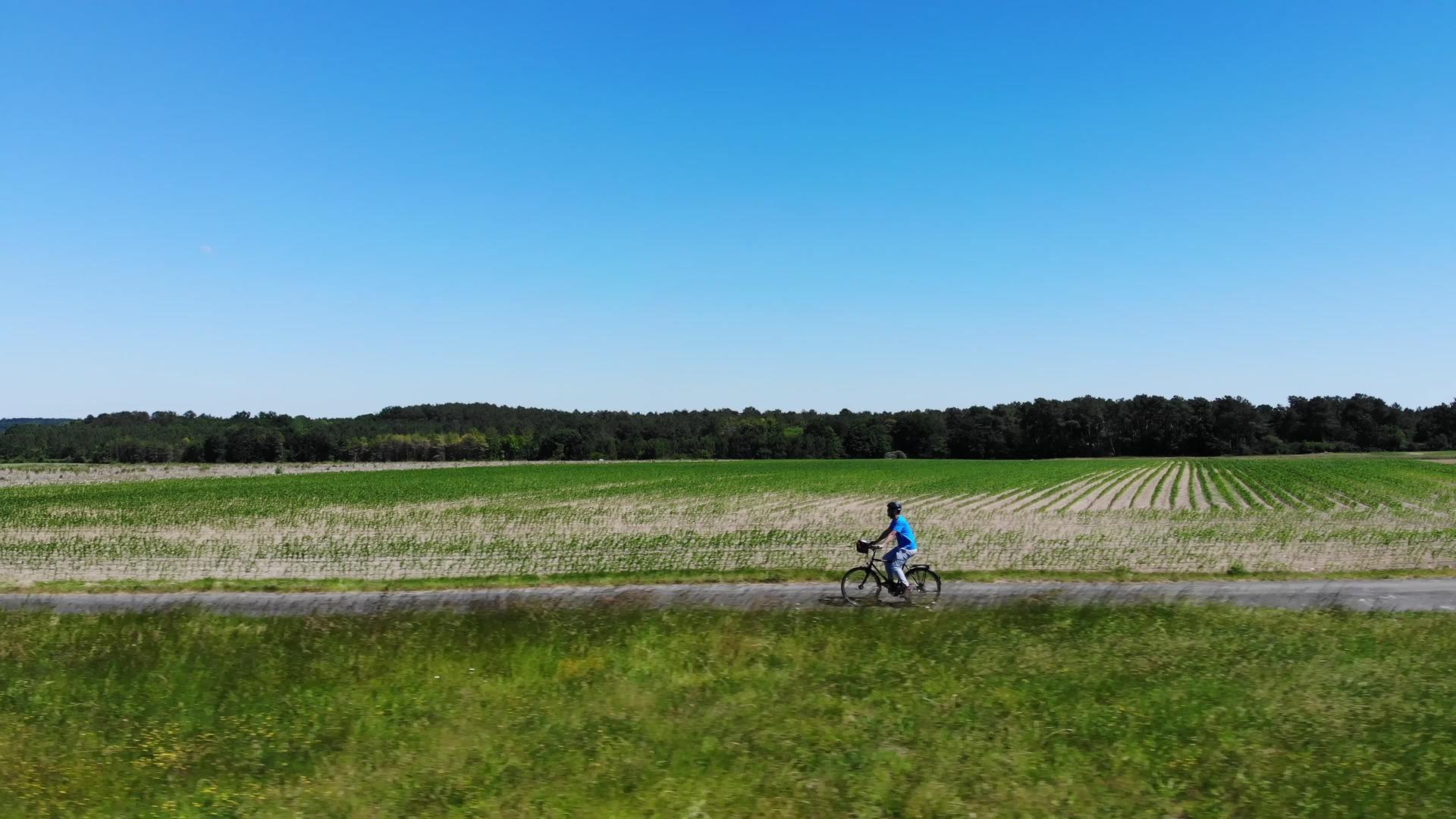 在空中不可辨认的人骑着绿色电动自行车穿过一片大草地视频的预览图