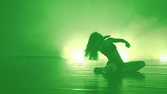 在烟雾舞台上年轻美丽的芭蕾舞演员在黑暗中跳舞视频的预览图