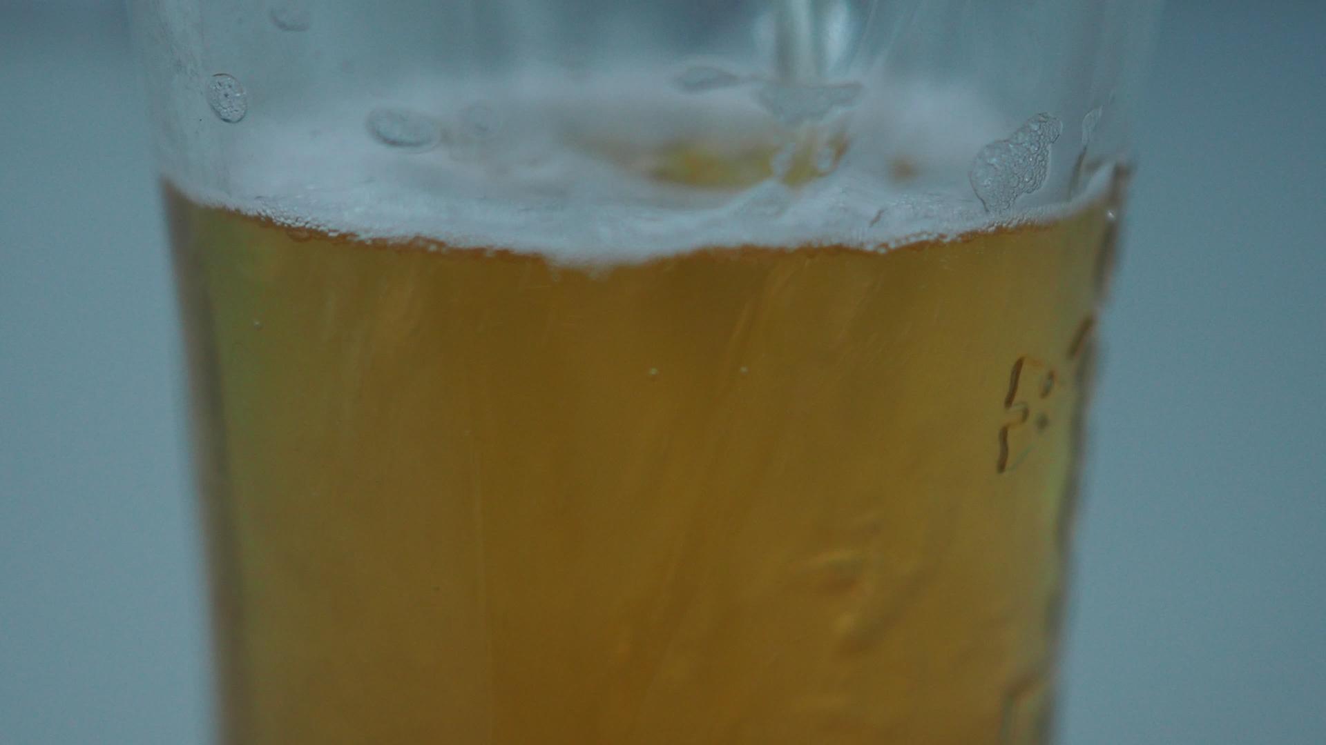 当啤酒倒入玻璃中时拍摄的视频关闭4k视频的预览图