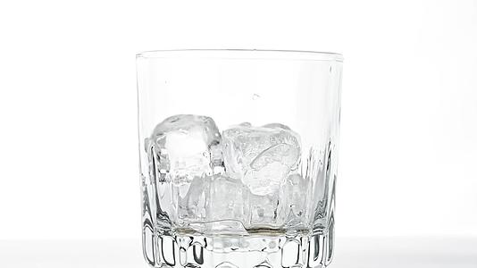 冰雪立方体落在空威士忌杯的白色玻璃中视频的预览图