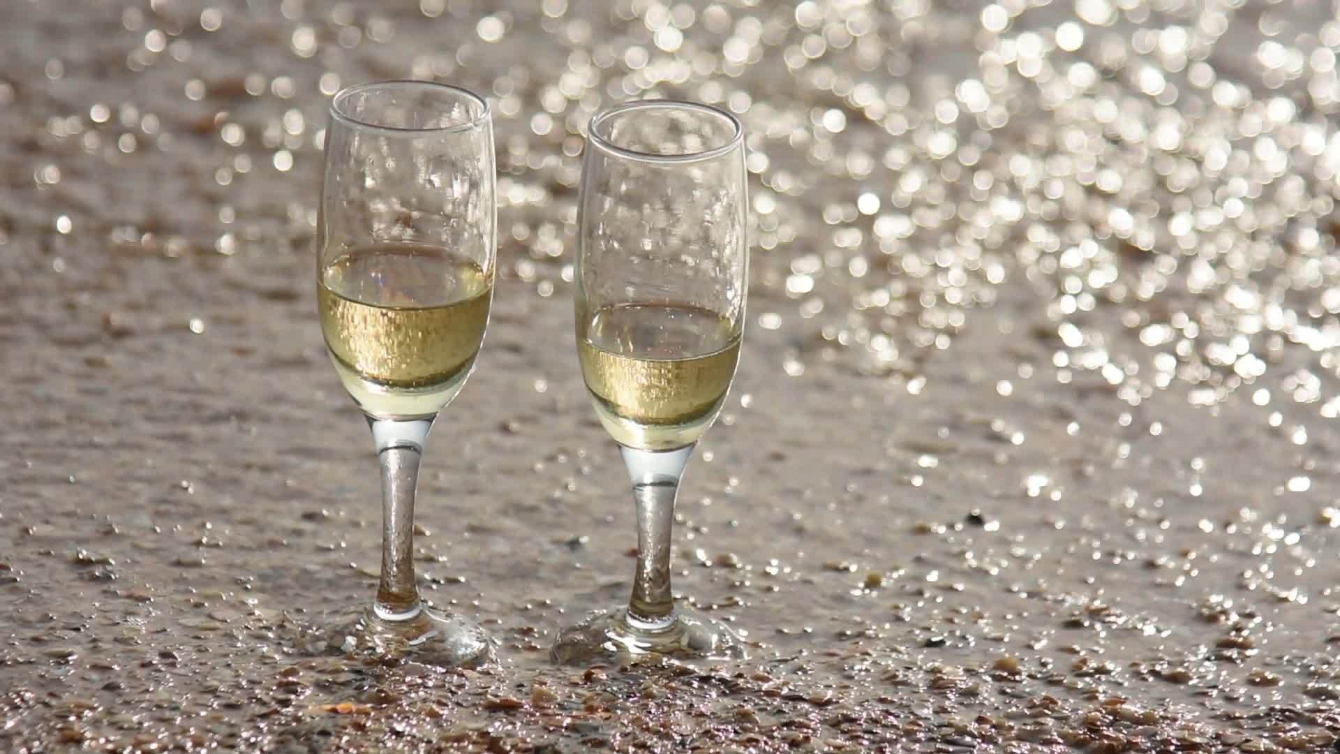 冲走两杯香槟中的一杯站在沙滩上的沙滩上视频的预览图